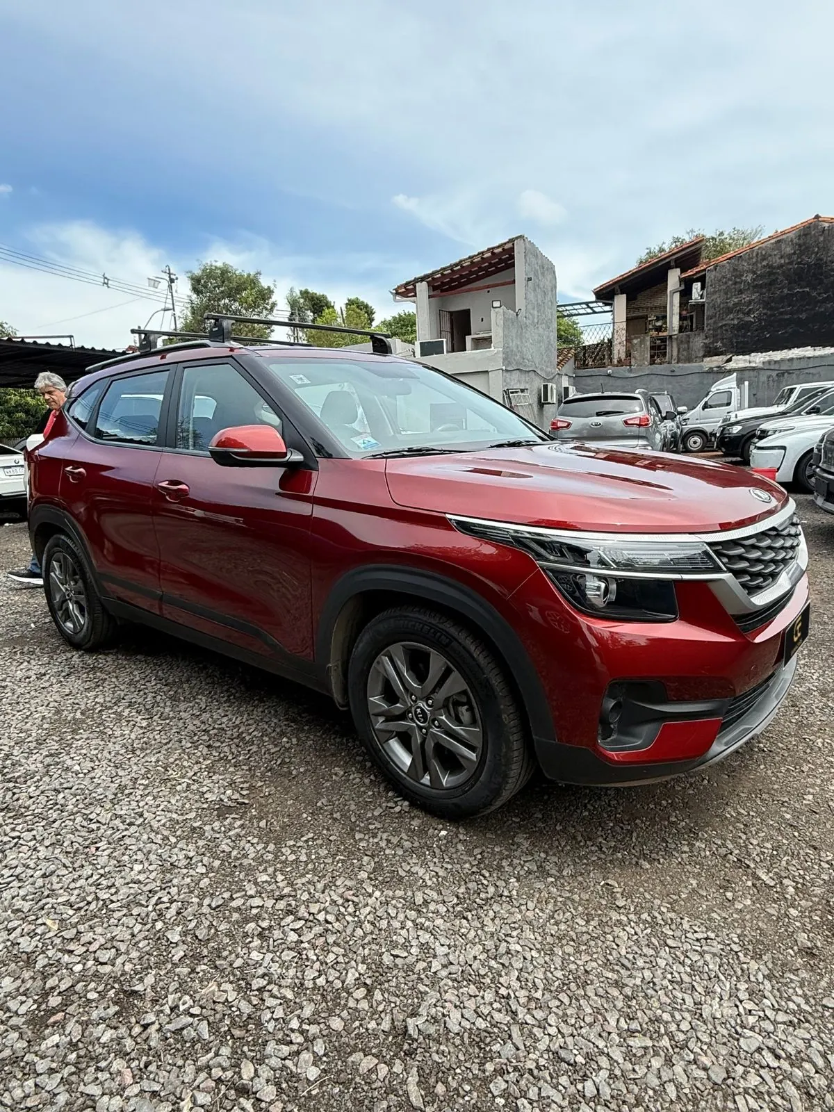 Kia Seltos rojo con barras de techo, vista lateral tres cuartos
