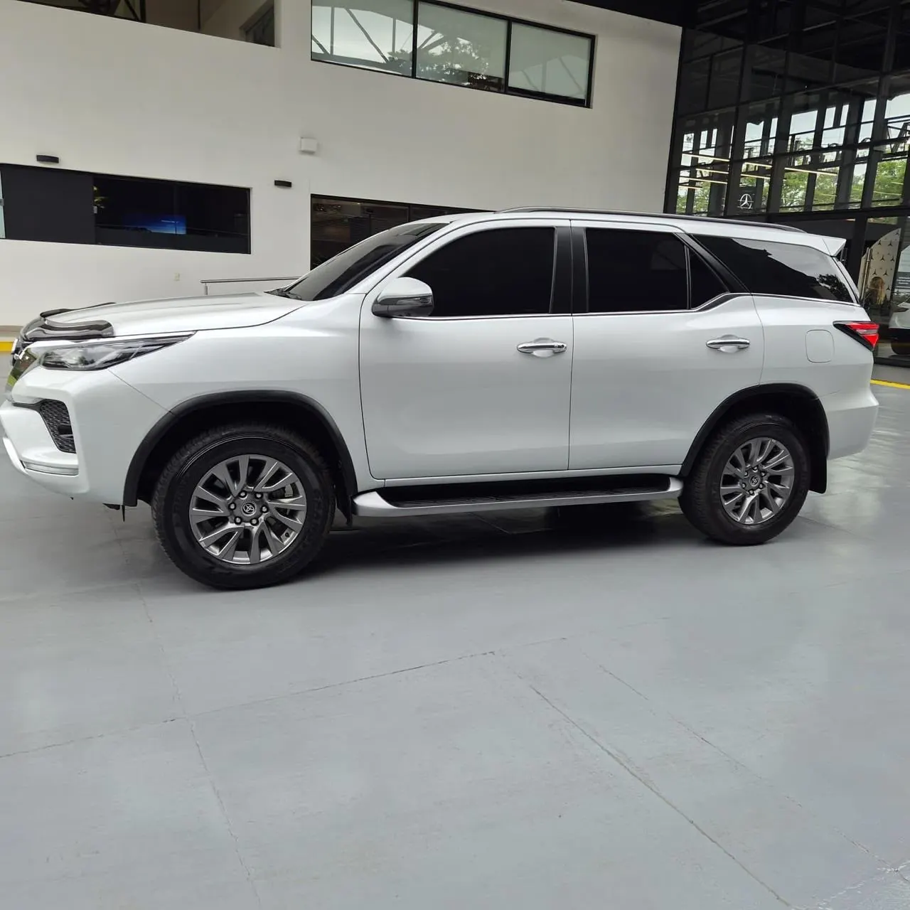 Toyota Fortuner SRV blanca, vista lateral con estribos y llantas de aleación